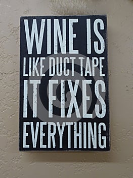 A sign with the saying Ã¢â¬ÅWine is like duct take it fixes everythingÃ¢â¬Â.
